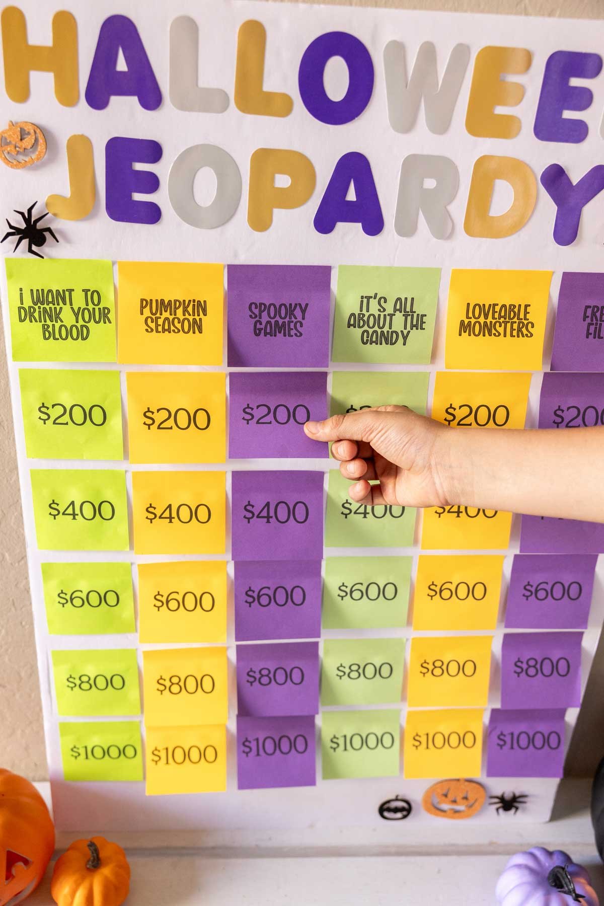 hand removing a post-it note from a Halloween Jeopardy board