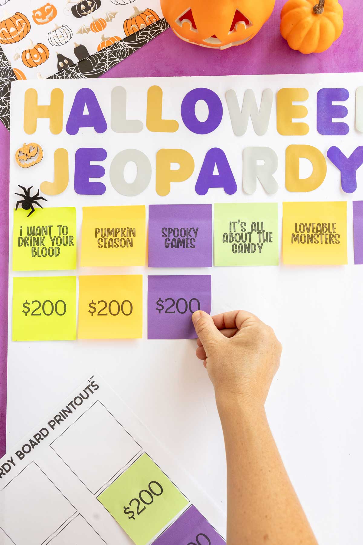 hand putting post-it notes on a Halloween Jeopardy board