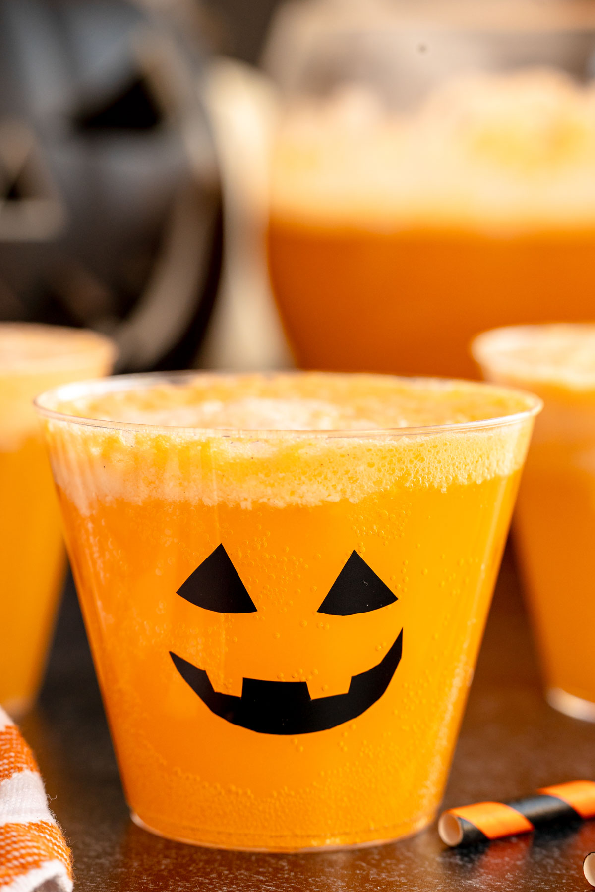 cup full of pumpkin punch with a jack o lantern face on it