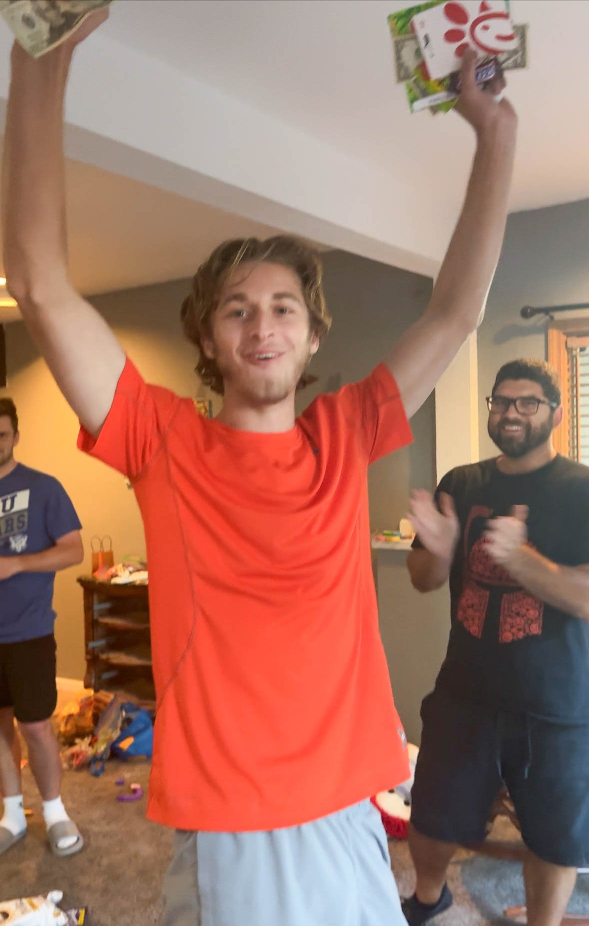 teen boy holding prizes in one hand while cheering