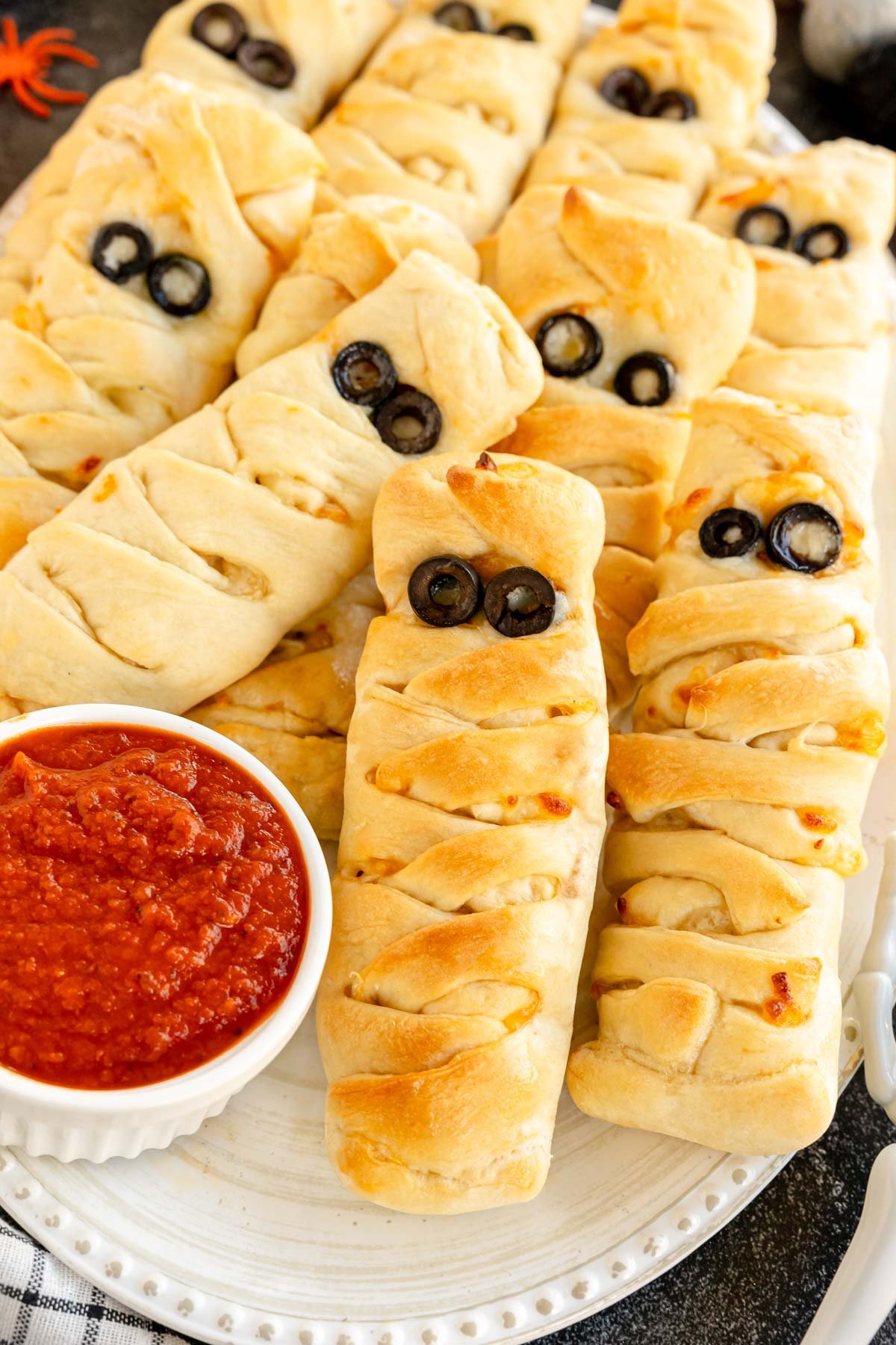 Halloween mummy pizza loaves with a cup of pizza sauce