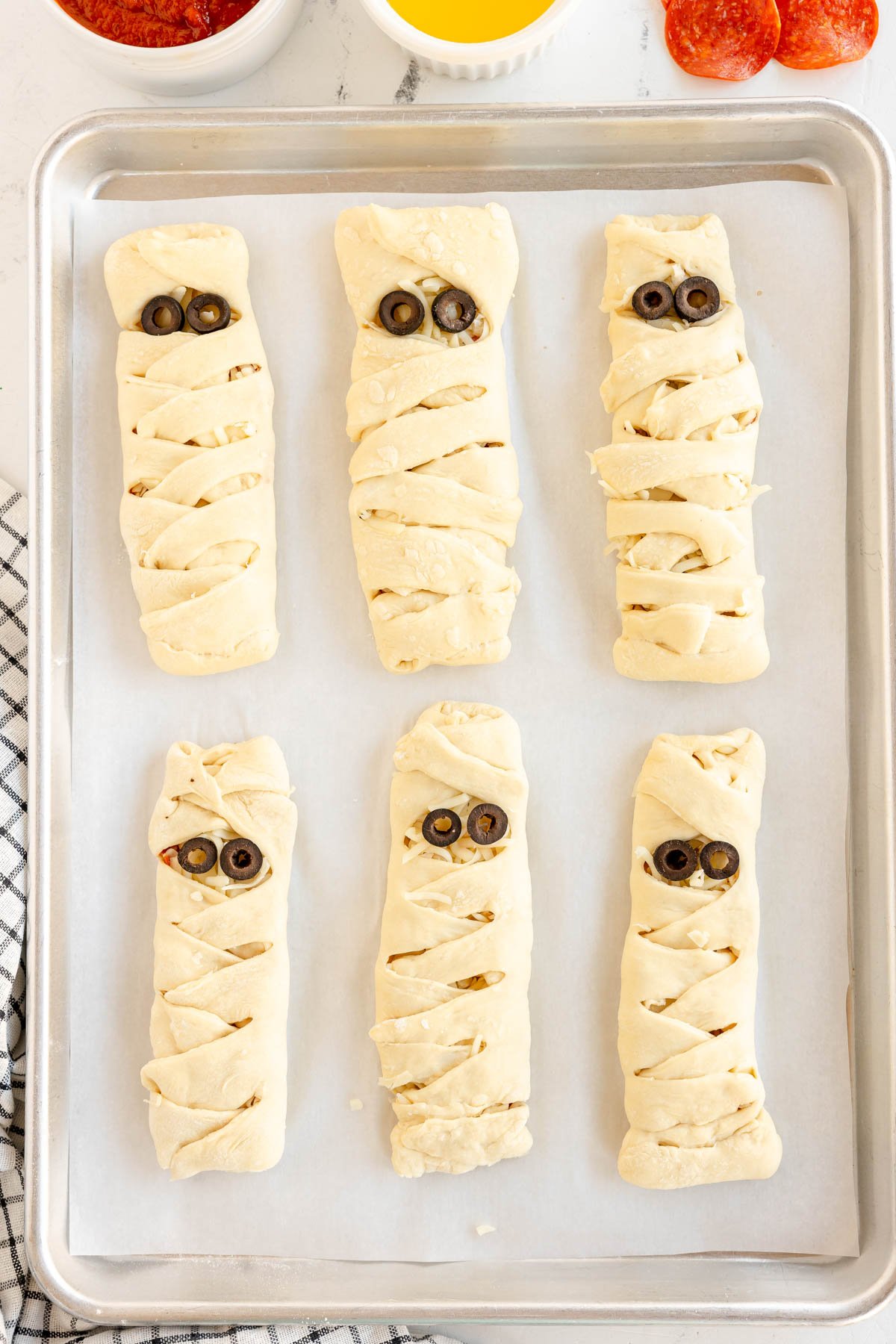 unbaked mummy pizza loaves with olive eyes