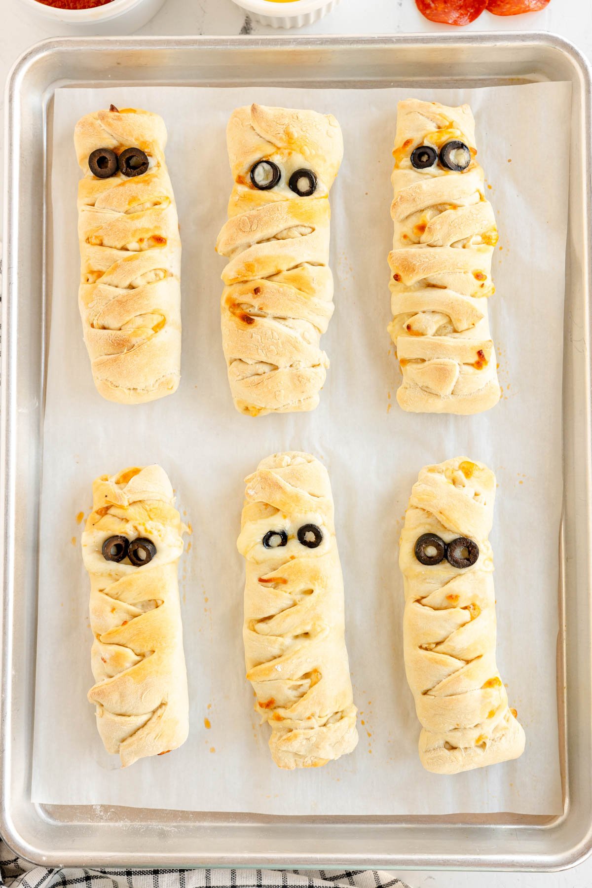 baked mummy pizza loaves on a parchment paper 