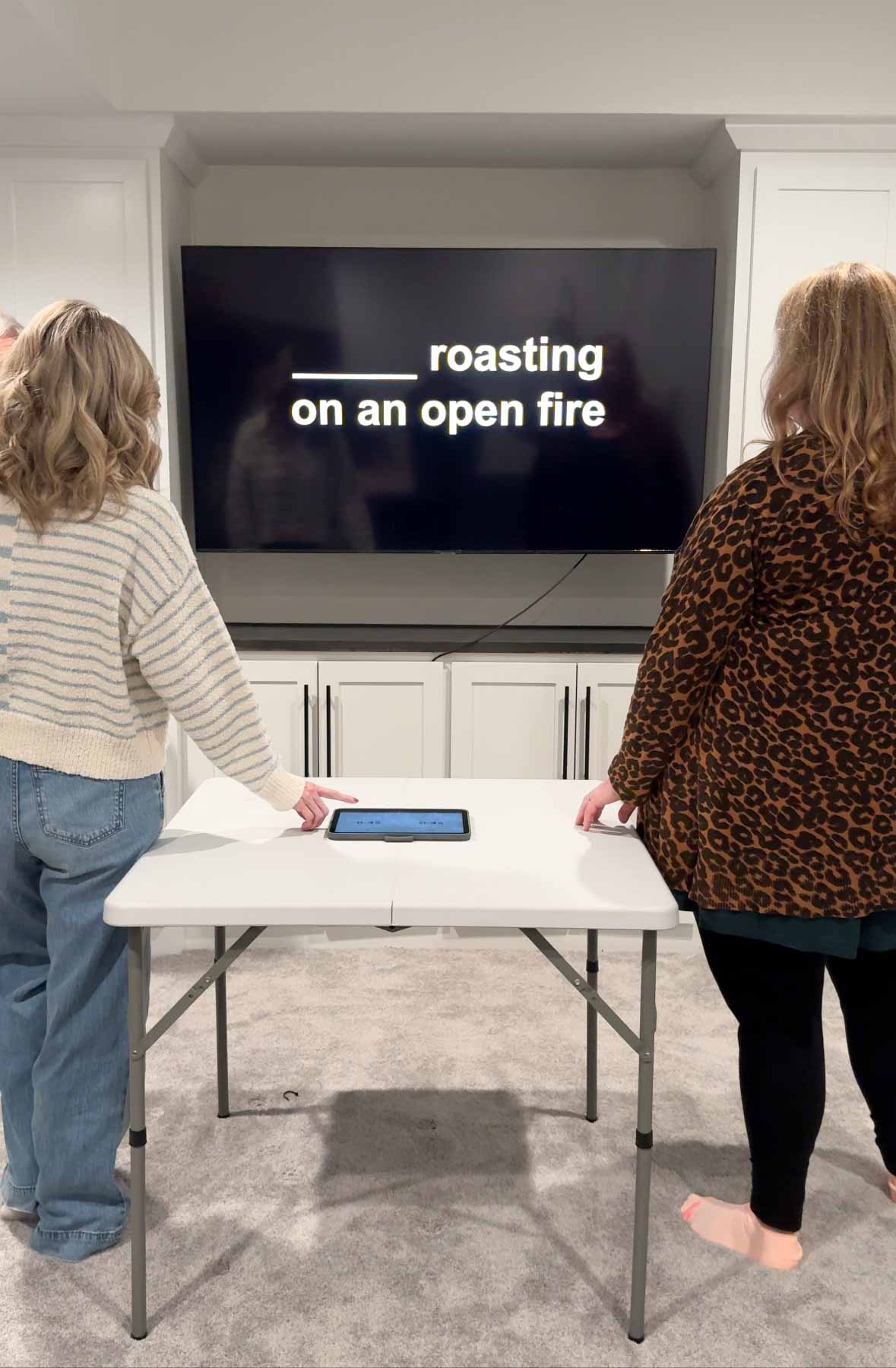 two people standing in front a TV with a CHristmas song lyric