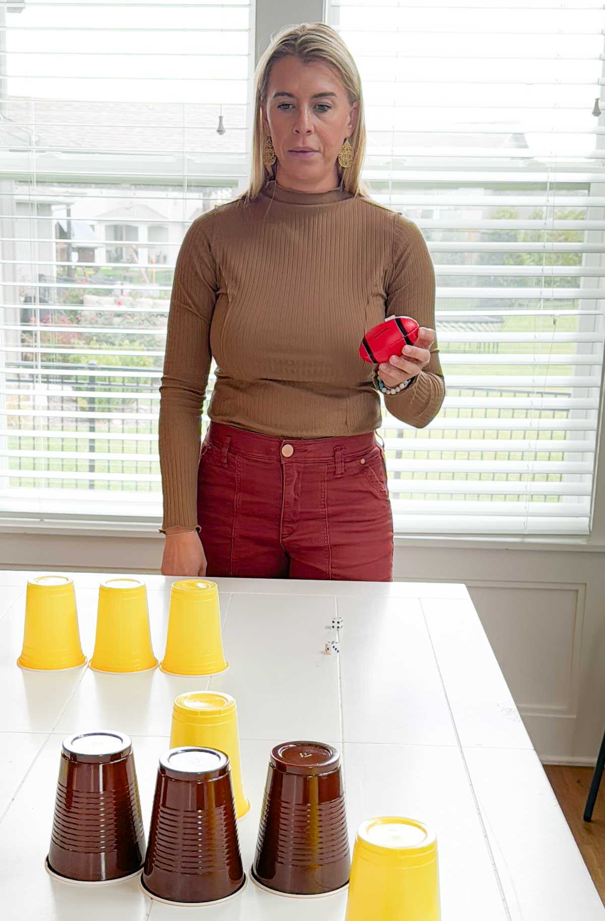 woman holding a football looking at brown and yellow cups