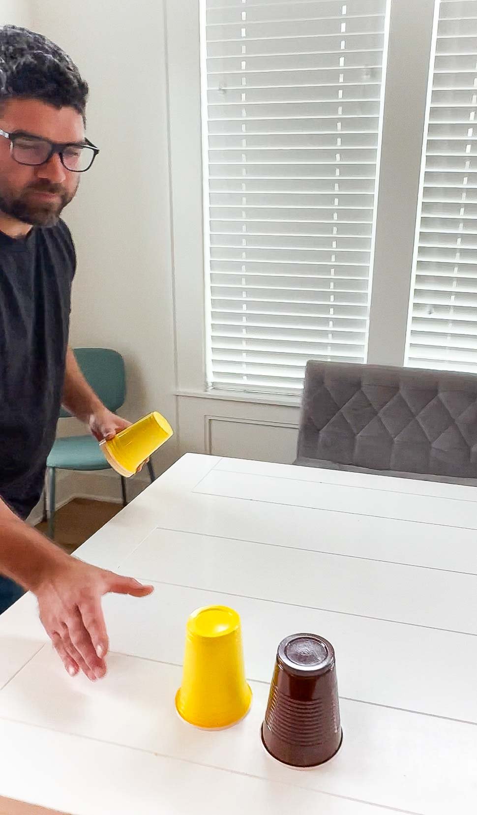 man sliding a yellow cup on a white table