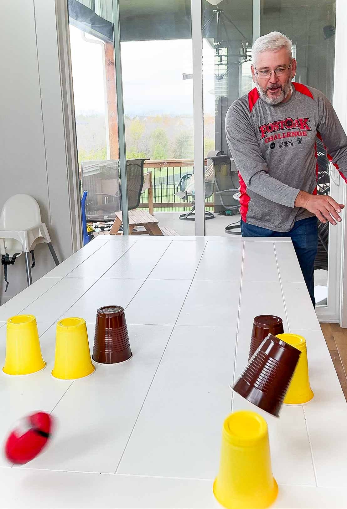 red football flying next to yellow and brown cups on a table