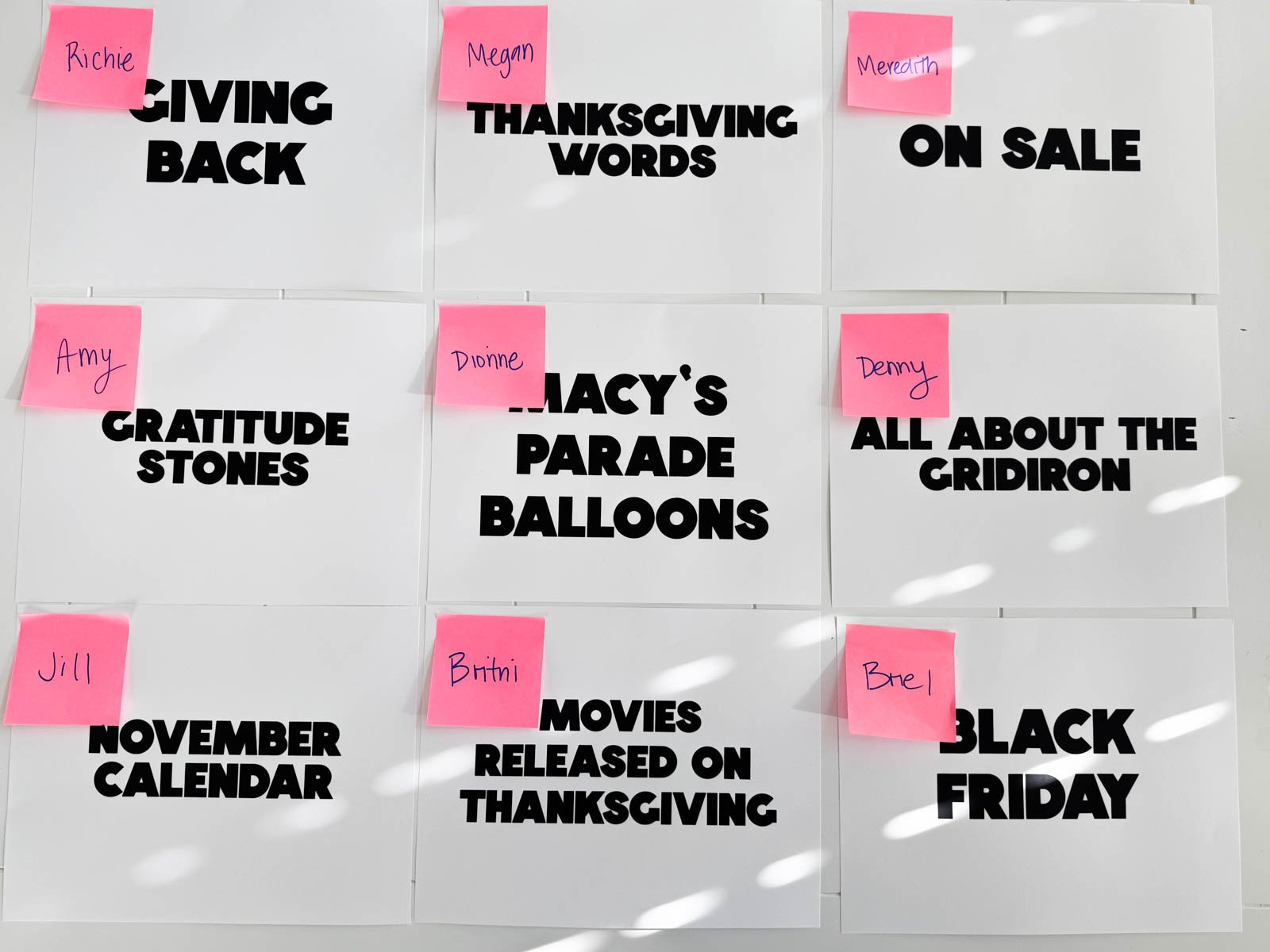 Thanksgiving categories on white pieces of paper with pink post-it notes