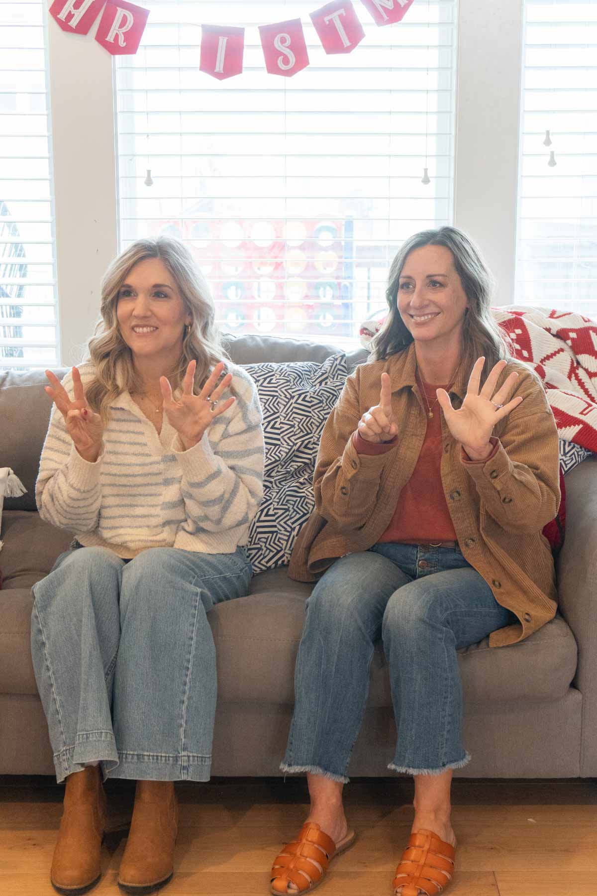 two women sitting on a couch holding up fingers 