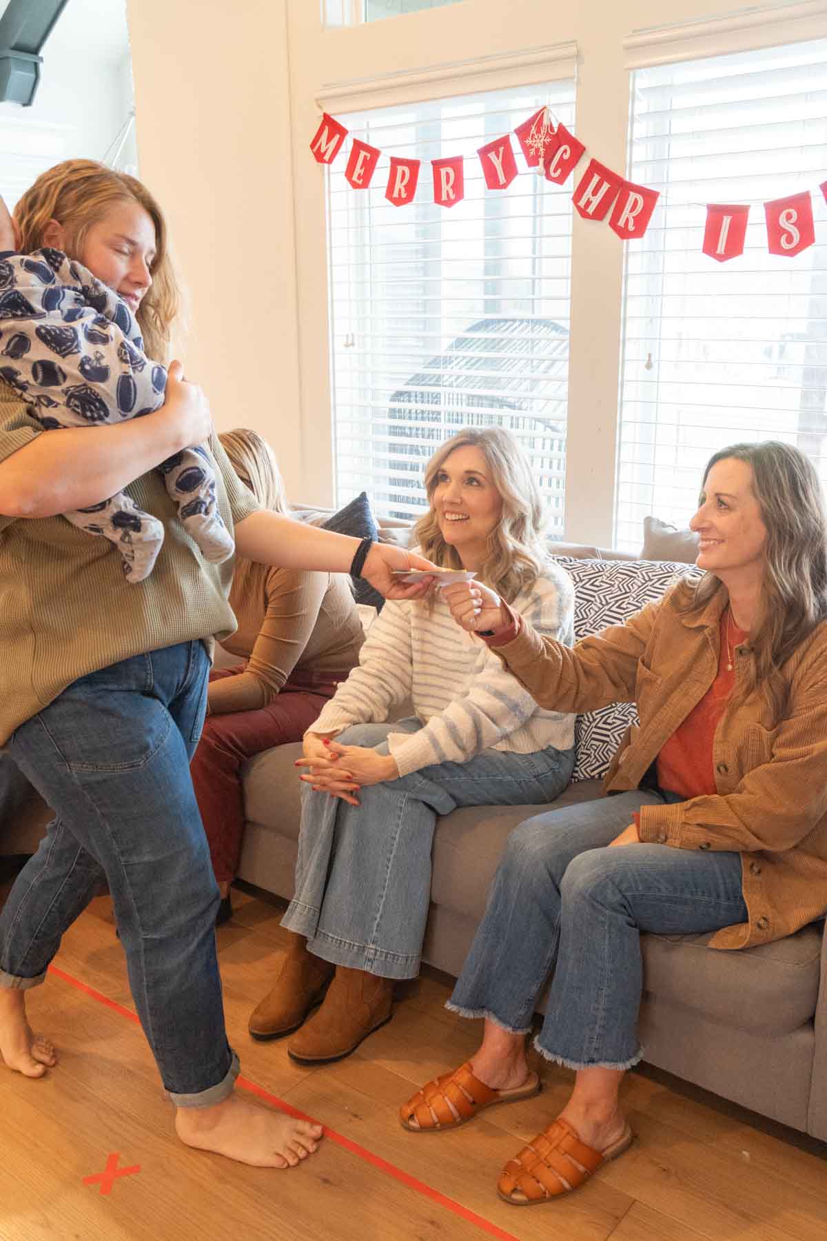 woman collecting play money from another woman who is sitting on a couch