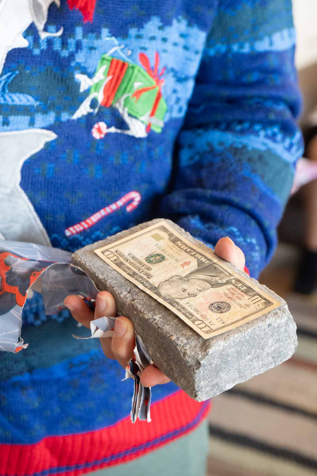 man holding a brick with cash on it