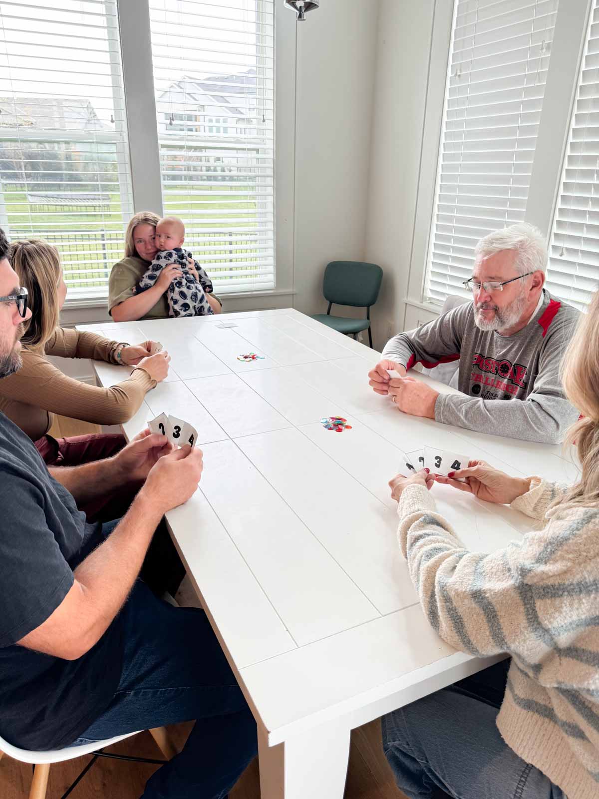 people sitting around a white table holding numbered cards