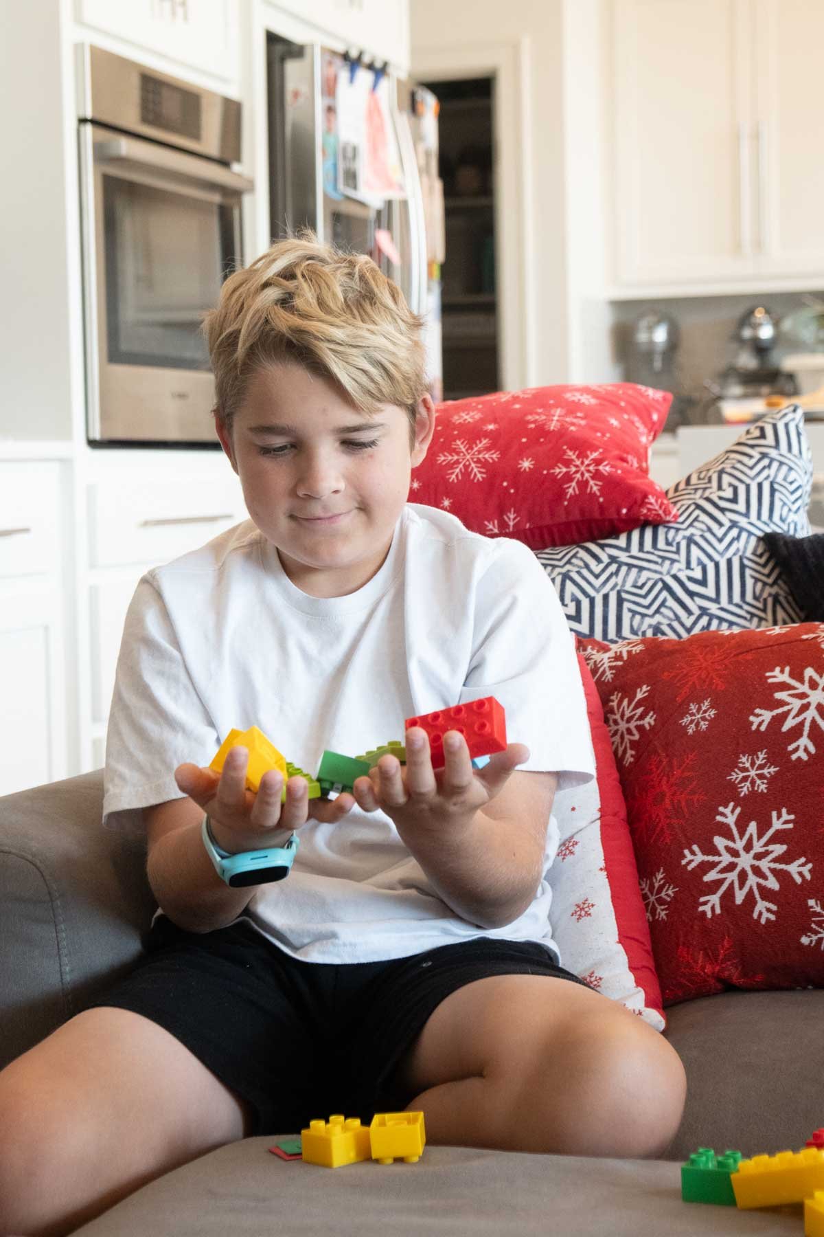 tween boy sitting on a couch with duplos