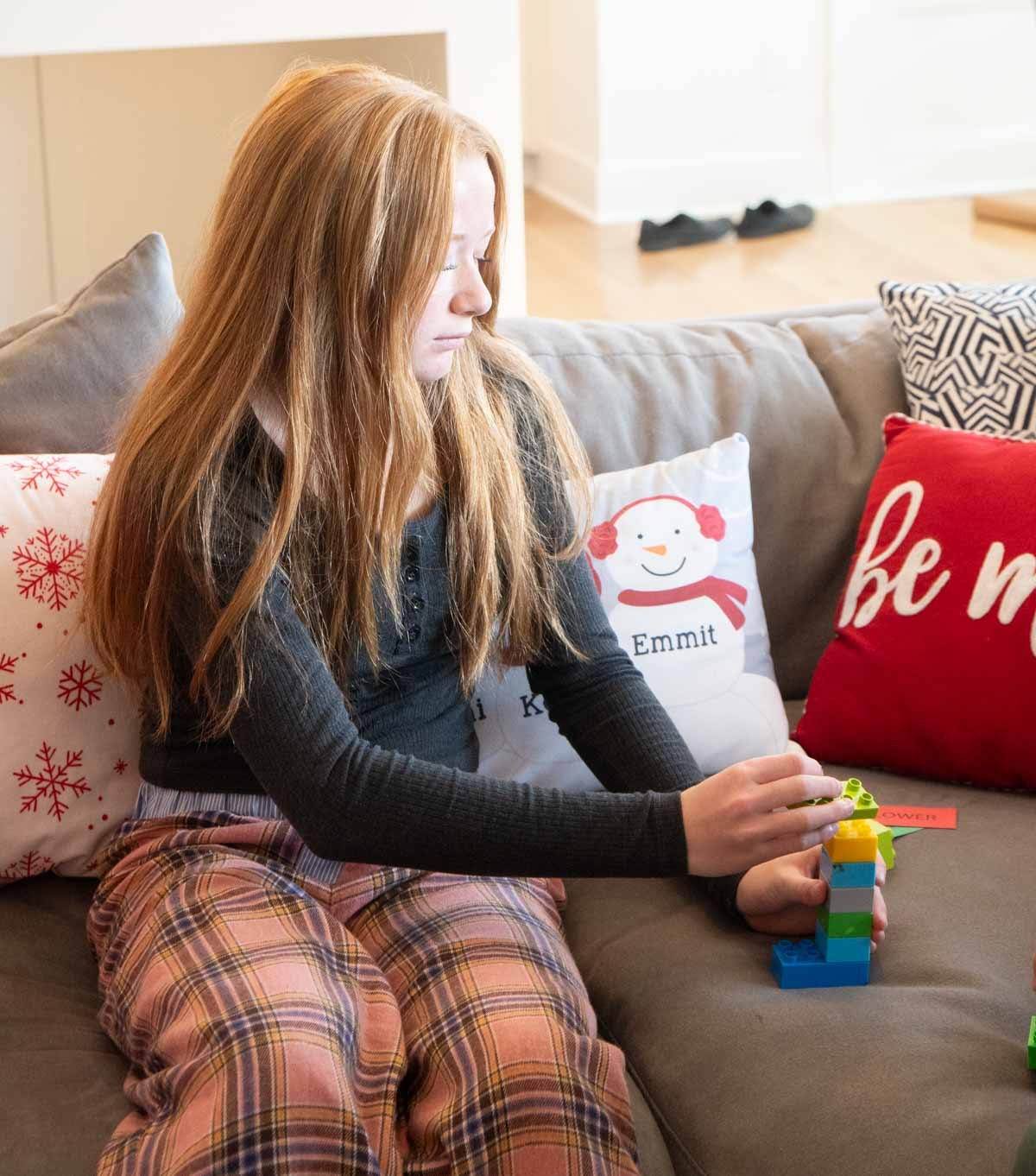 girl adding a block to her stack on a couch