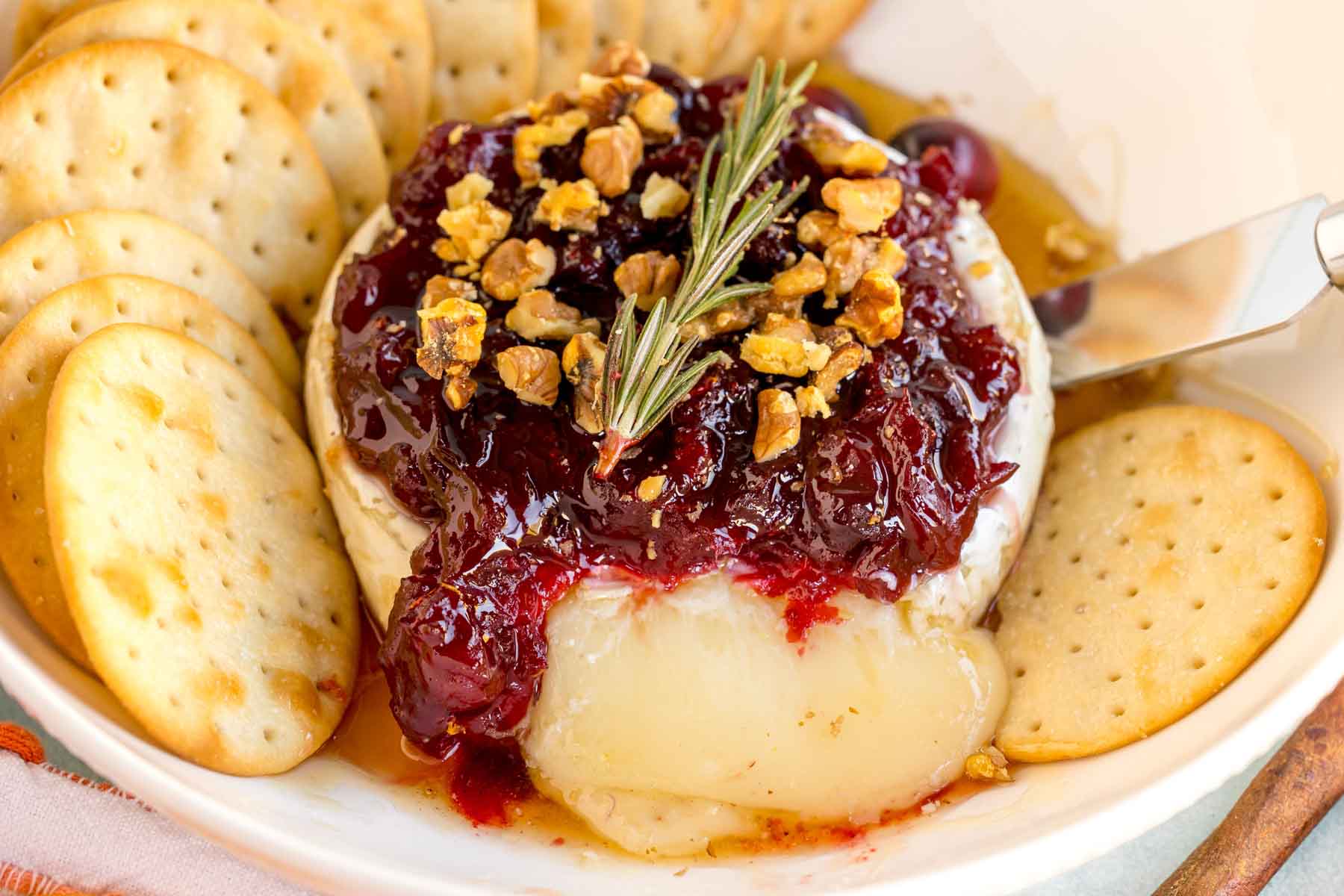 baked brie with honey and cranberry sauce surrounded by crackers