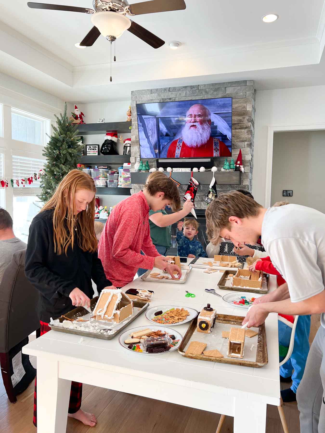 white table with teens making gingerbread houses on top of it