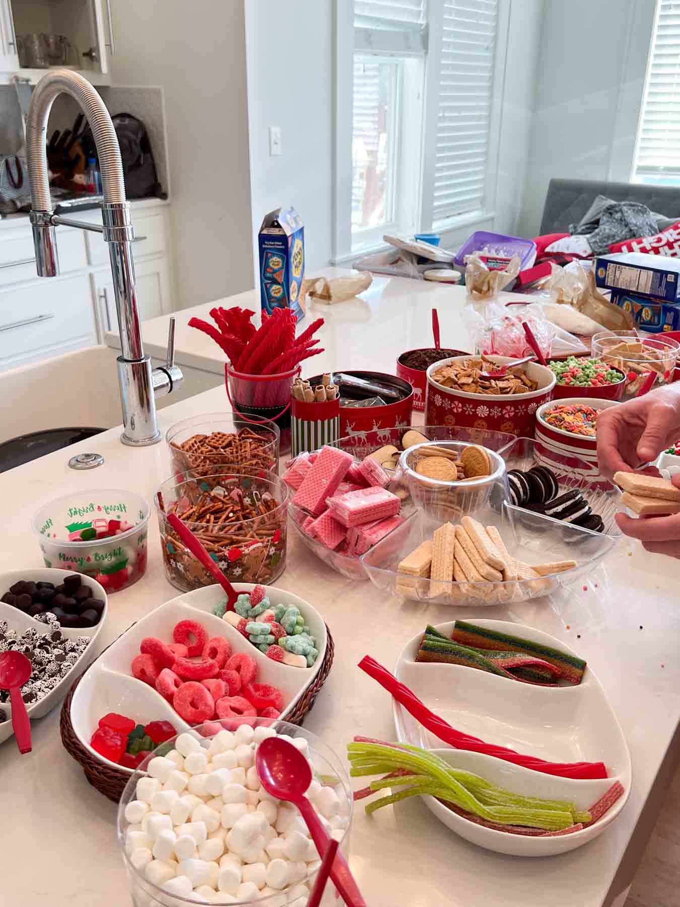 white kitchen island with bowls and dishes full of candies and gingerbread house toppings 