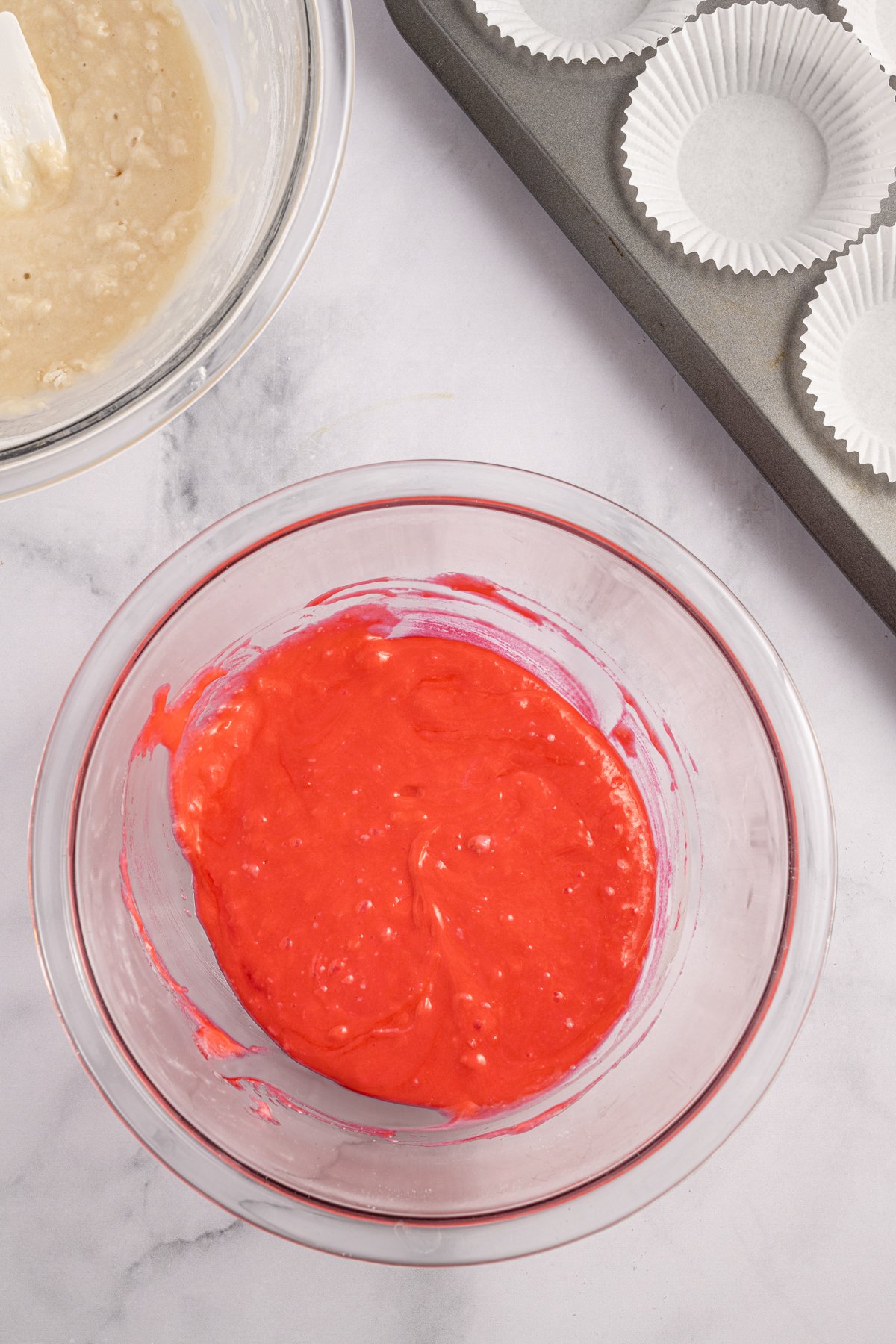 red cupcake batter in a glass bowl