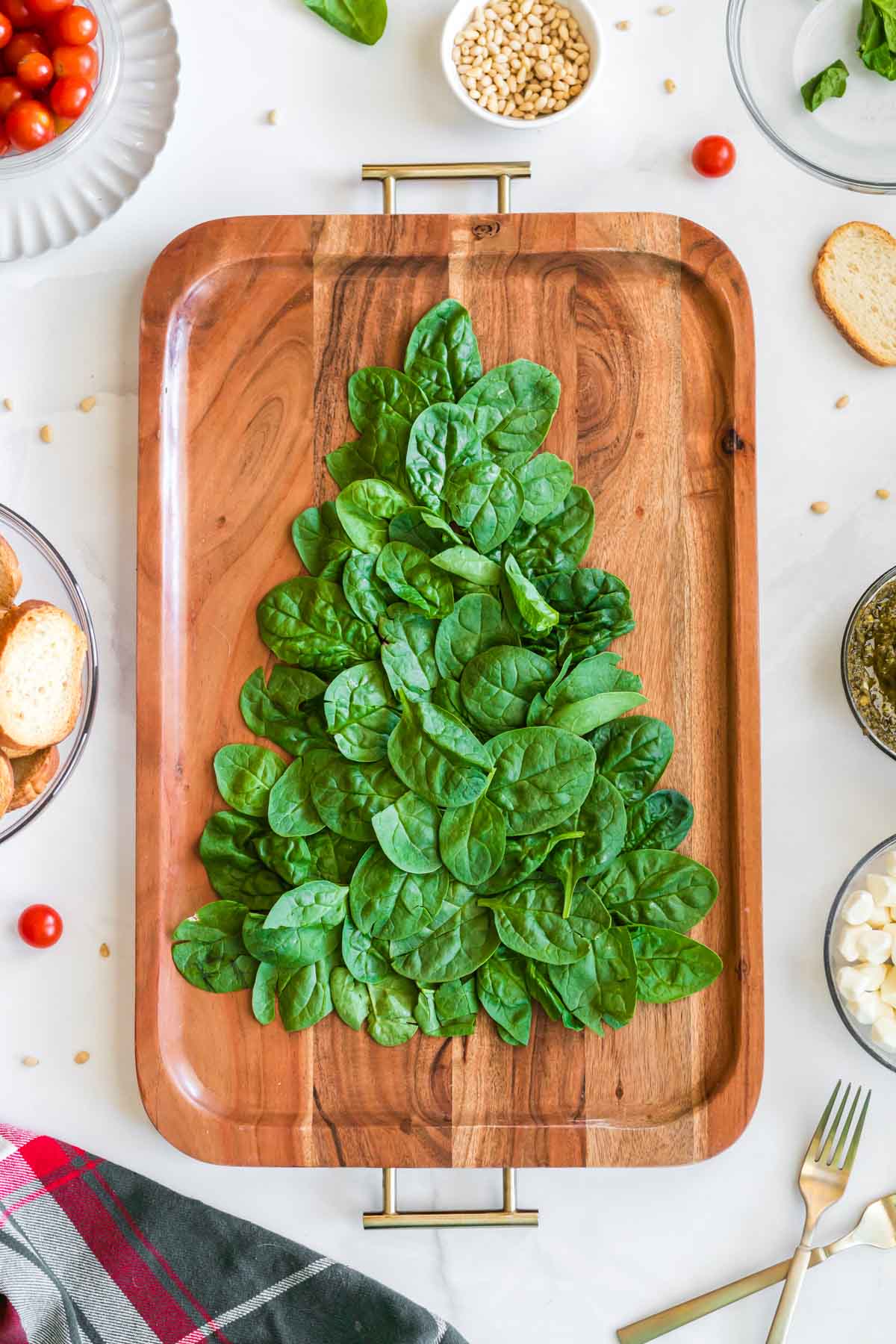 baby spinach on a charcuterie board in the shape of a Christmas tree