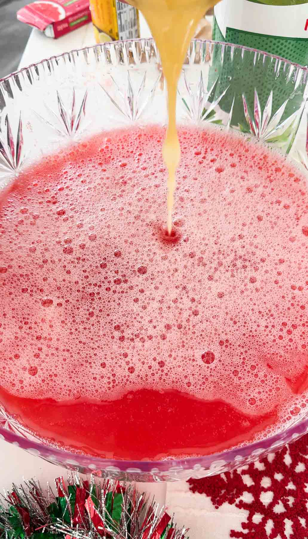 pouring juice into a red Christmas punch bowl