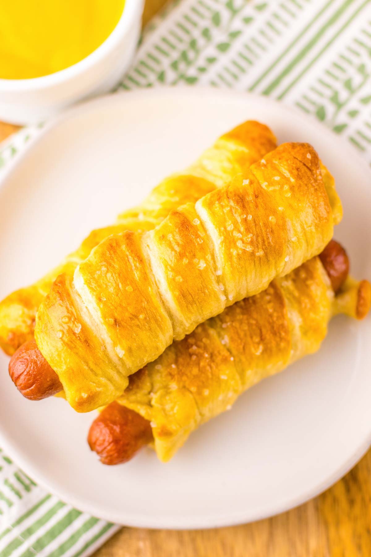 three stacked pretzel dogs on a plate