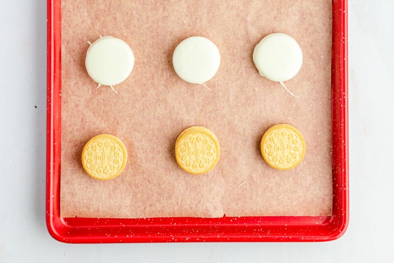 white chocolate dipped Oreos on a baking sheet