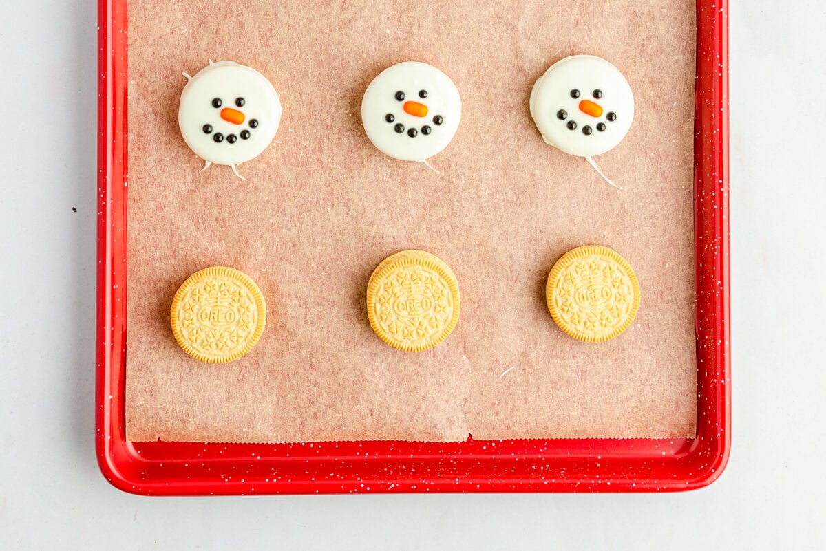 Oreo snowmen with faces on a baking sheet