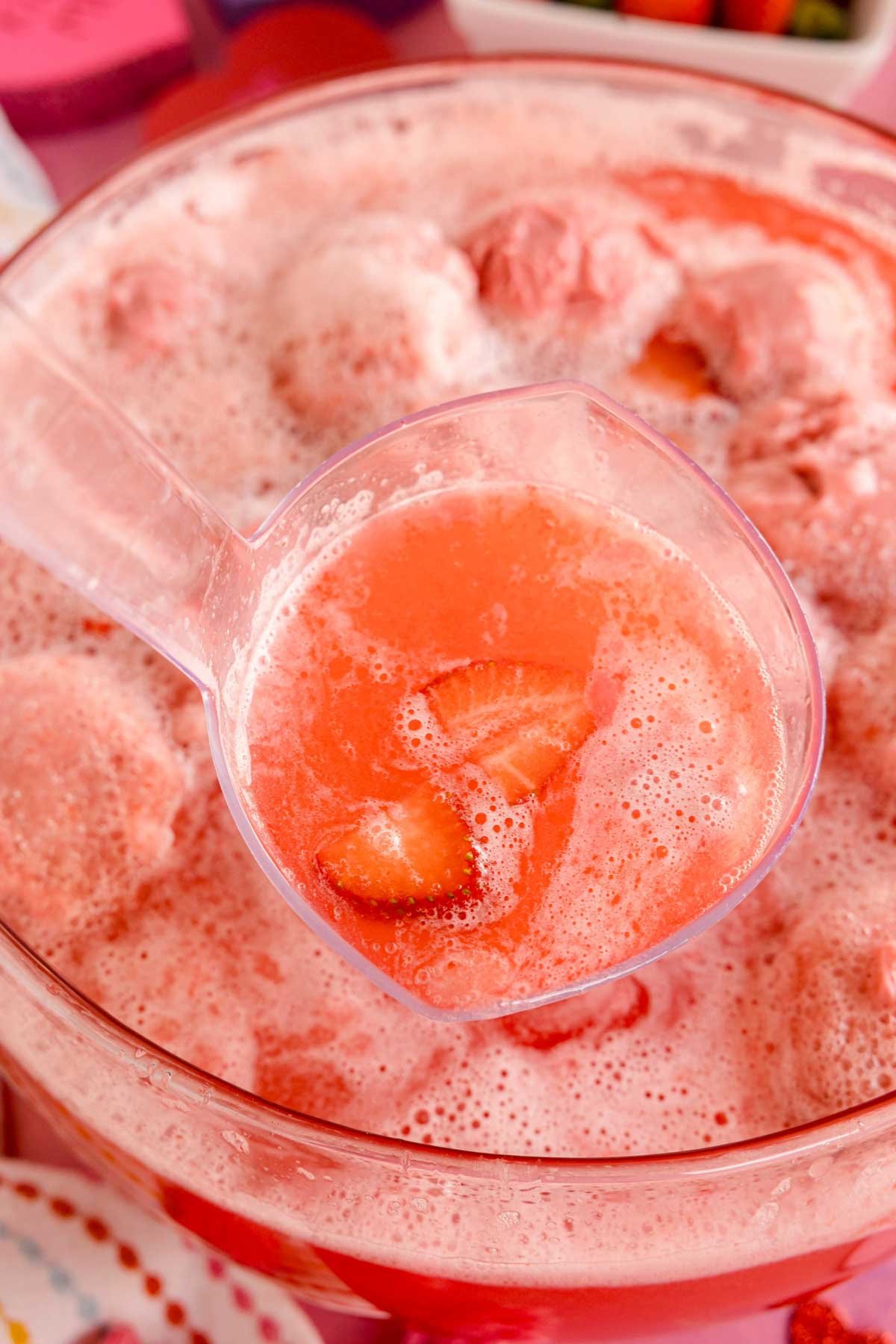 scooping strawberry punch out of a punch bowl