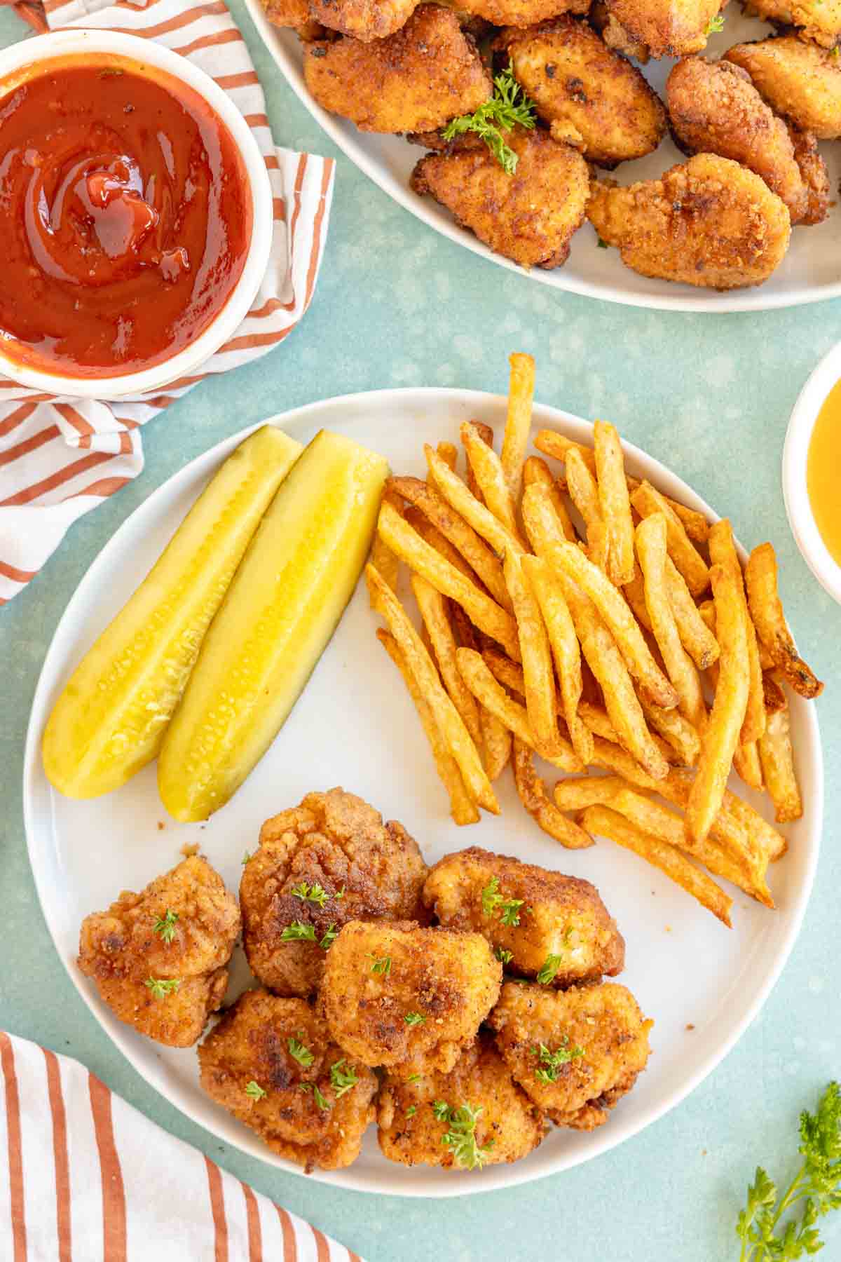 white plate with copycat chick-fil-a nuggets, french fries, and pickle slices 